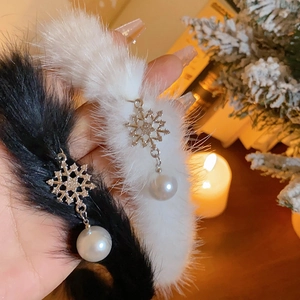 Détail de boucles d'oreilles pelucheuses avec flocons de neige et perles de Noël