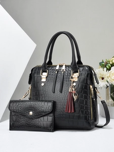 Detailed close-up of black crocodile pattern leather handbag with gold hardware and tassel