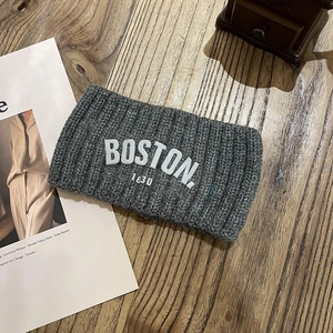 Détail du bandeau en tricot gris avec broderie BOSTON 1630 sur fond de bois