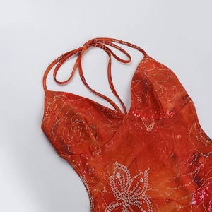 Détail macro d'une robe dos nu avec imprimé floral rouge et finitions en strass