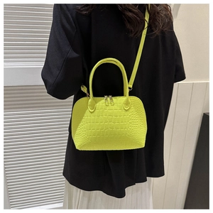 Neon lime shell bag with crocodile texture worn as a crossbody with a minimalist outfit