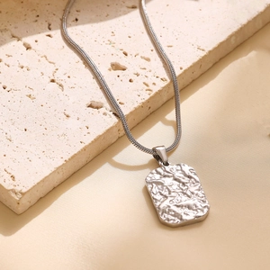 Detailed macro view of a silver snake chain with a rectangular lava textured pendant