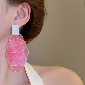 Detail view of long layered pink sequin tassel earrings with white rectangular studs