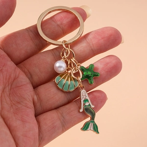 Golden mermaid keychain with pearl shell starfish charms on pink background