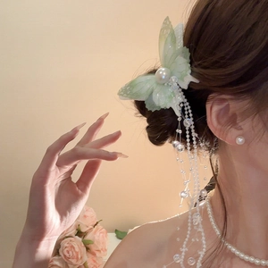 Detailed close-up of a butterfly mesh hair clip with long pearl tassels on a female model
