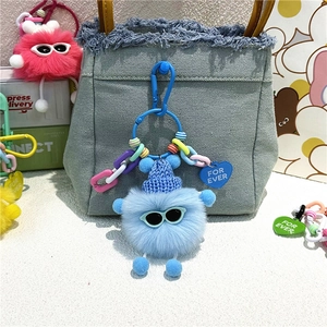 Porte-clés boule de suie bleue avec lunettes de soleil accroché sur un sac en jean