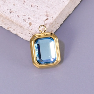 Detailed macro of gold rectangular pendant with vibrant blue gemstone on stone base