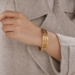 Close-up of a gold-plated stainless steel cuff bracelet featuring a Celtic knot design