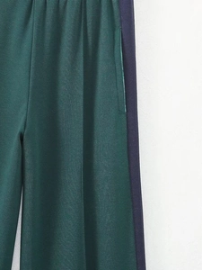 Gros plan détaillé du pantalon vert foncé avec bandes latérales bleu marine et poche cachée