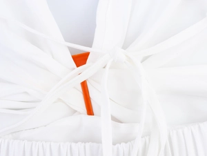 Dettaglio di un abito bianco da spiaggia con lacci sulla schiena e tessuto in chiffon