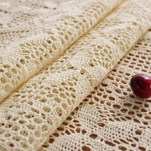 Macro shot of beige crochet table runner with intricate hollow lace and red berry detail