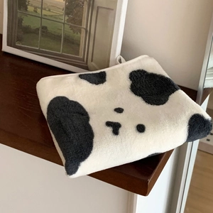 Detail of soft coral fleece towel featuring a cute black and white cow animal pattern