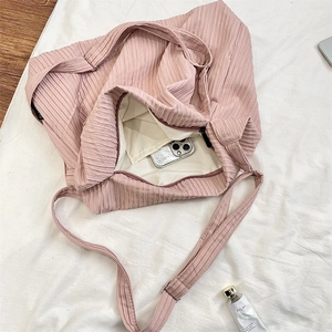 Detail of pink pleated canvas tote bag showing interior compartment with a smartphone