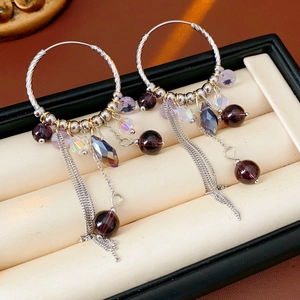 Détail de boucles d'oreilles bohèmes à pampilles avec cristaux violets en boîte à bijoux