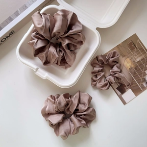 Close-up of elegant champagne silk scrunchies in a minimalist lifestyle setting