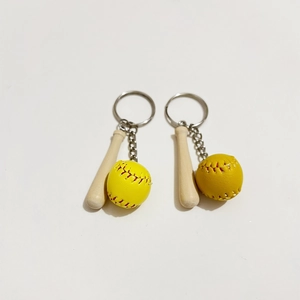 Close-up of wooden baseball bat keychain with yellow softball and red stitching detail