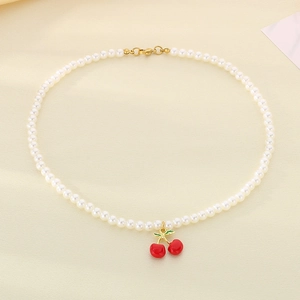 Detail showing white pearl necklace with bright red cherry pendant and gold clasp