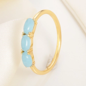 Elegant gold metal ring with three vertical light blue oval gemstones in a 4-claw setting