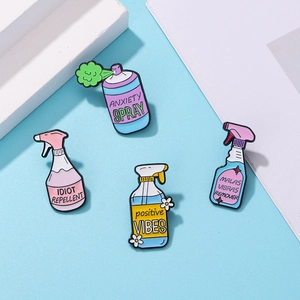 Macro detail of enamel spray bottle pins featuring creative typography and pop art style