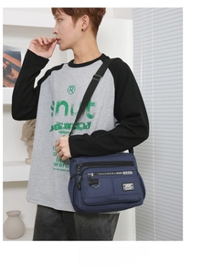 Detail of multi-pocket navy crossbody bag with metal zippers and adjustable strap
