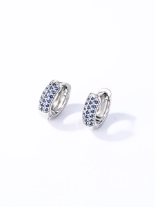 Vue détaillée de créoles en argent serties de zircons bleus sur fond blanc épuré
