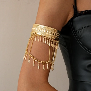 Detailed view of bohemian gold arm cuff with intricate metal fringe and feather charms