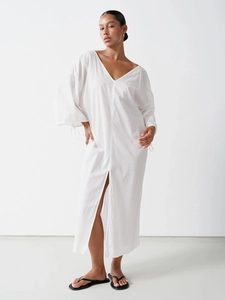 Detail of white cotton V-neck dress with long sleeves and elegant side slit for summer