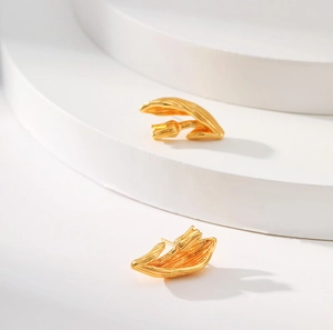 Macro detail of 18K gold plated tulip bud earrings on a minimalist white pedestal