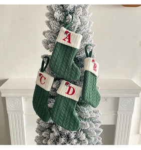 Close-up of green cable-knit Christmas stockings with red embroidered alphabet letters