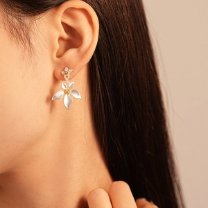 Detailed close-up of a silver flower petal drop earring worn by a model in natural light