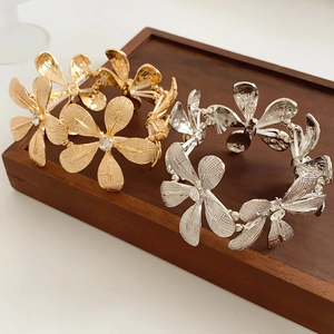 Makroaufnahme von Gold- und Silberblumenarmbändern mit Kristallen auf Holztablett