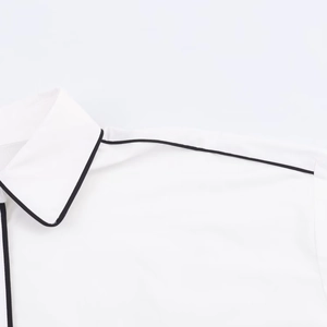 Detail view of white poplin shirt featuring black contrast piping on collar and shoulder