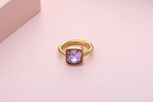 Detail of a square-cut pink zircon center stone on a polished gold stainless steel ring