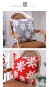 Détail de housses de coussin de Noël grises et rouges avec flocons sur chaise en bois