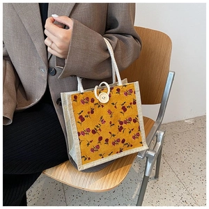 Detail of yellow floral canvas handbag with white cotton rope handle and wood button