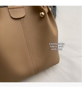Detailed close-up of brown lychee texture leather bucket bag with gold stud and stitching