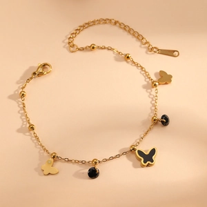 Bracelet doré élégant avec papillons et perles noires, fermoir mousqueton sur fond neutre