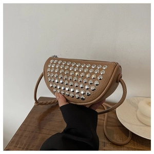Detail shot of light brown lychee leather crescent bag with silver stud accents