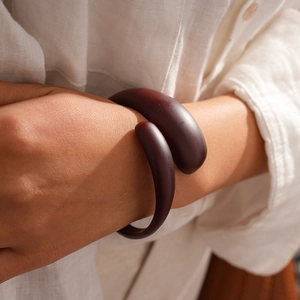 Detail of chunky dark brown spiral acrylic resin bangle on a model's wrist