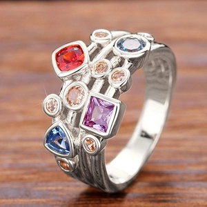 Primer plano macro de anillo plateado con piedras preciosas de colores y varias formas