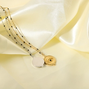 Gold and silver evil eye necklaces with black zircon pendants on beige silk fabric