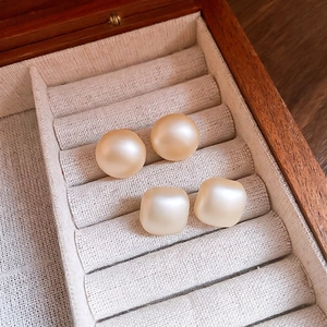 Elegant set of round and square cream pearl stud earrings in a wooden jewelry box display