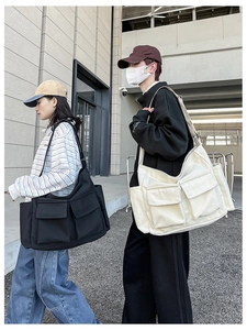 Detail view of large canvas messenger bags with front pockets in black and cream beige