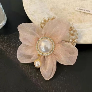Vue détaillée d'un chouchou en organza rose avec perle centrale et accents de diamants