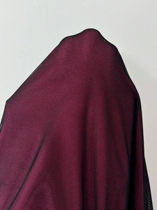 Detail of burgundy dress fabric featuring a delicate black mesh overlay design