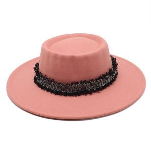 Detalle de sombrero de lana rosa con cinta de tweed blanco y negro en primer plano