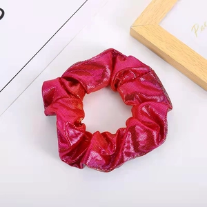 Detailed view of rose red metallic scrunchie with glitter texture on white background