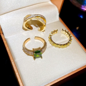Detailed view of three 18k gold plated adjustable rings with emerald and zircon stones