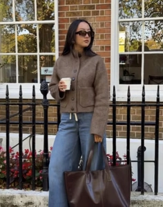 Vue de rue d'un cardigan marron boutonné avec un grand sac cabas en cuir marron assorti