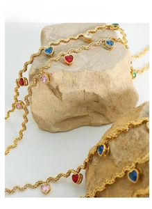 Detail of gold twisted rope chain with colorful heart-shaped zirconia charms on stones